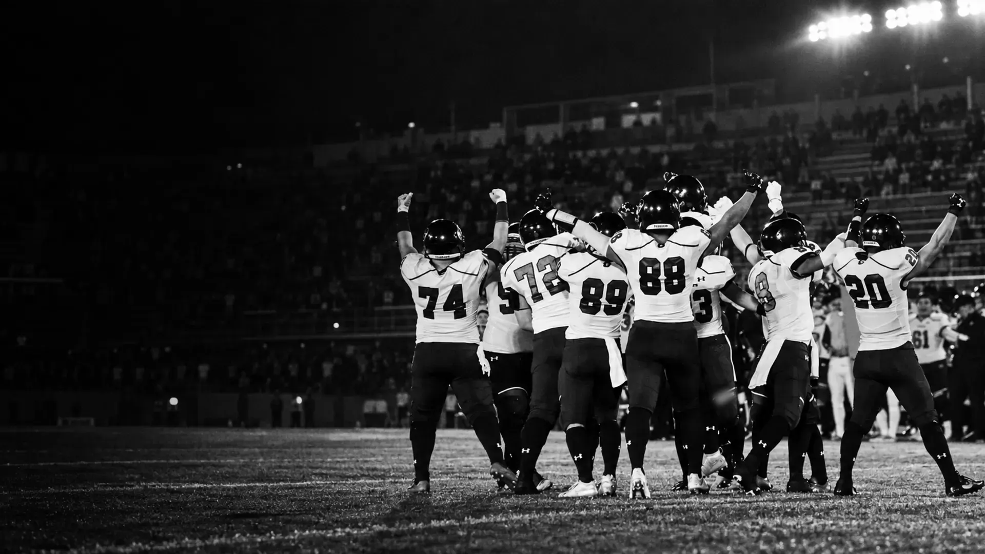 試合のあと、両腕を上げて喜び合うアメリカンフットボール部の選手たち